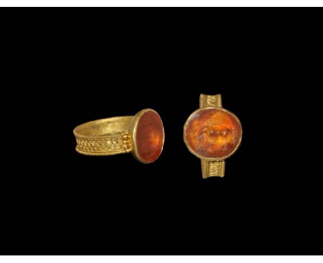 3rd-4th century AD. A flat-section hoop with beaded wire borders and filigree meander, dished bezel with inset carnelian cloi