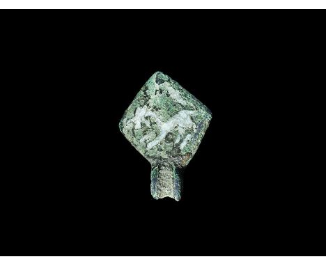 13th-14th century AD. A bronze lozengiform plaque with stud to the reverse, hinge below; the field with a white enamelled run