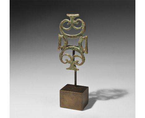 1st-2nd century AD. A flat-section plaque with two D-shaped loops connecting two openwork pelta-shaped scrolled panels with T
