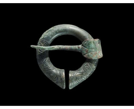 10th-12th century AD. A round-section penannular shank with expending finials, running spiral ornament to the upper faces; th
