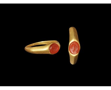 3rd century AD. A keeled D-section gold hoop with carinated shoulders, elliptical plaque with inset carnelian, intaglio profi