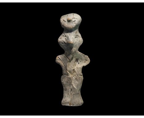 Neolithic, 6th-5th millennium BC. A terracotta robed figure with stub arms and two heads, one above the other, with pinched f