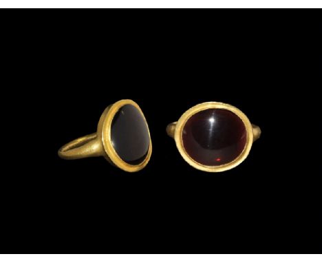 4th-3rd century BC. A narrow round-section hoop with expanding shoulders supporting a discoid plaque with inset garnet caboch