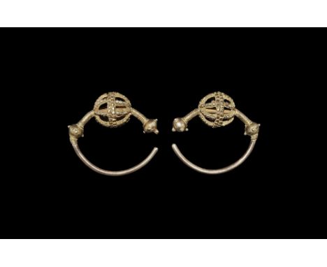10th-12th century AD. A matched pair of Slavic type silver-gilt earrings, each formed as a round-section bar with two solid b