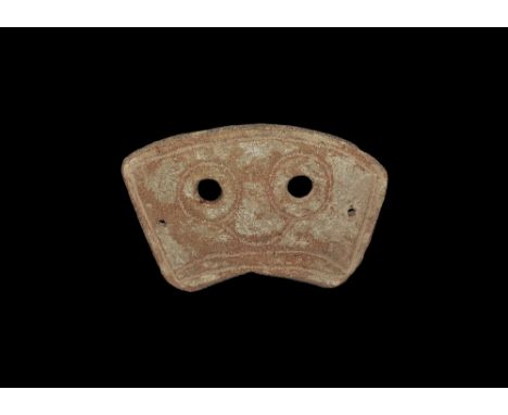 4th-3rd century BC. A rectangular slightly curved ceramic mask with two eye-holes and incised stylised facial details; pierce