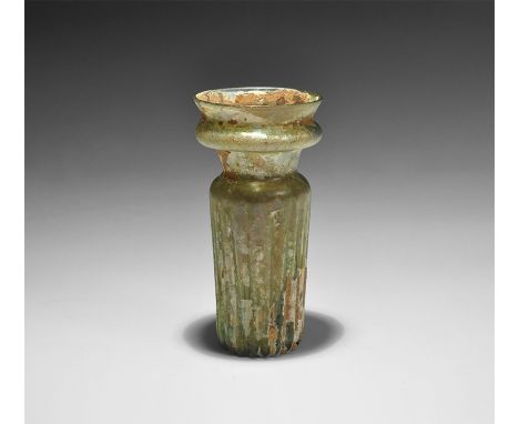 4th century AD. An iridescent green-glass jar with tubular body and vertical ribbing, dimple base, narrow neck with rounded m