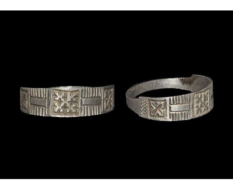 12th century AD. A flat-section silver hoop with stepped shoulders, plaque with hatched panels, two voided saltire motifs abo