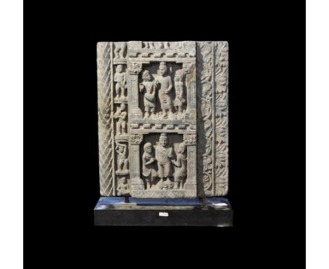 2nd-3rd century AD. A grey schist relief panel with two central registers each depicting the Buddha in the centre with two fi