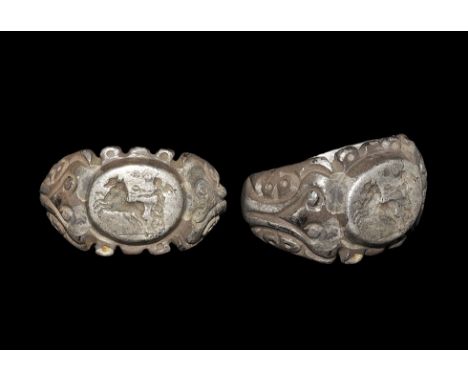 3rd century AD. A substantial D-section silver hoop expanding to keeled shoulders with scrolls and tendrils, discoid plaque w