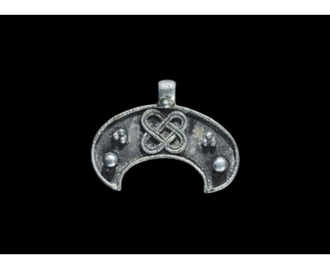 9th-12th century AD. A flat-section crescentic plaque with integral loop, raised beaded wire borders, applied granule detaili