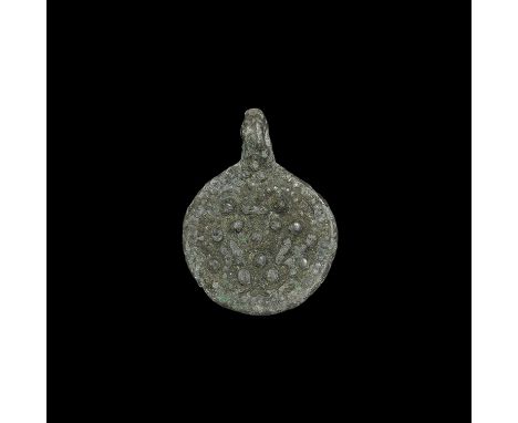 11th-12th century AD. A flat-section bronze discoid plaque with pierced lug above, high-relief design of trefoil pellets and 
