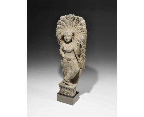 1st-4th century AD. A carved schist frieze fragment depicting a yakshi standing bare-chested in a loose skirt, weight borne o