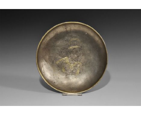 5th-3rd century BC. A silver footed dish with flared base, thickened parcel-gilt rim, incised parcel-gilt design of a royal b