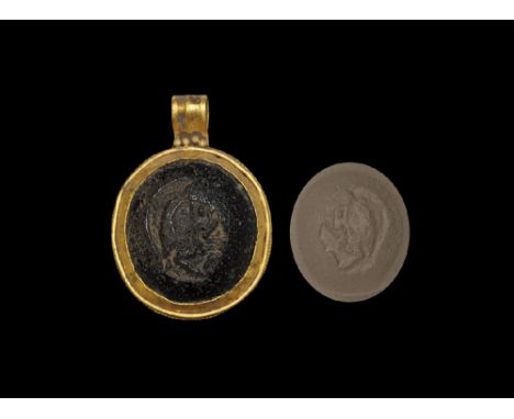 1st-2nd century AD. A discoid gold plaque with beaded border, ribbed loop with granule detailing, flared cell with black glas