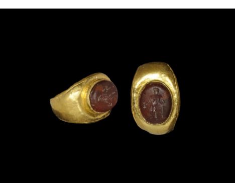 1st-2nd century AD. A C-section gold hoop with expanding shoulders, flat plaque with applied cell, inset glass cabochon, inta