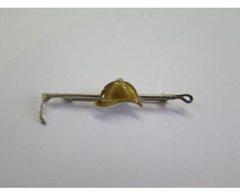 A bar brooch in the form of a riding crop, mounted with enamel jockey cap
