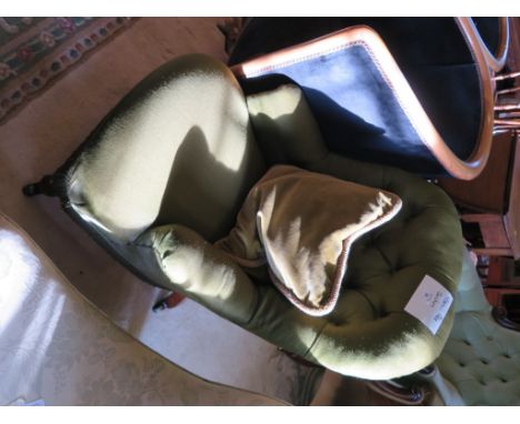 A late Victorian button back nursing chair, in dark green upholstery, on turned legs and castors