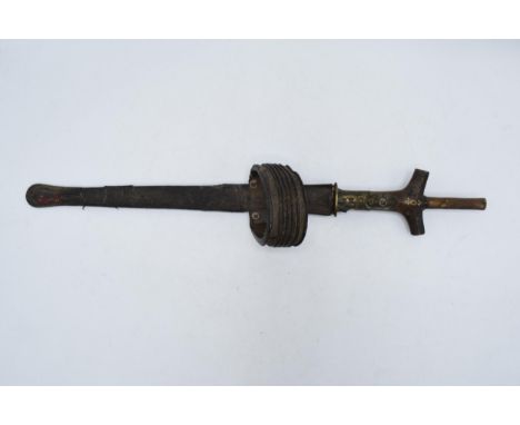 A 20th century sword in scabbard with brass inlay in the wooden handle and steel blade, believed to be of African origin, 47c