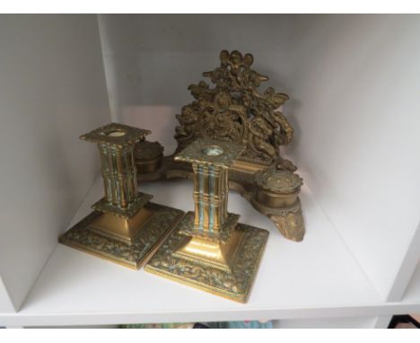 An embossed brass desk stand with letter rack, inkwell detail and a pair of Victorian pillar form candlesticks (3)