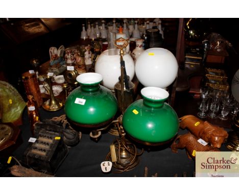 A dual oil lamp converted to electricity with green glass shades; and two other oil lamps with milk glass shades