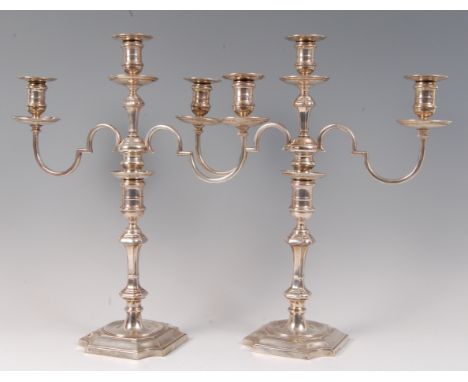 A pair of silver pedestal three light candelabra, in the early 18th century style, having detached sconces and multi-knopped 