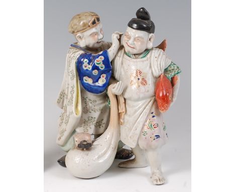 A Japanese late Meiji period stoneware figure group of a pair of street-vendors, one holding a carp under his arm, enamel dec