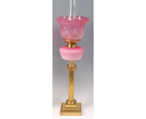 A Victorian brass pedestal oil lamp, having cranberry tinted shade and pink opaline glass reservoir to a reeded column and st