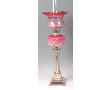 A silver plated pedestal oil lamp, having cranberry tinted acid etched shade and pink opaline glass reservoir to a reeded col