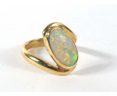 A modern yellow metal crossover ring set oval opal, ring size Q,7.7 gms