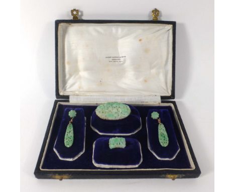 A suite of late 19th/early 20th century yellow metal mounted Chinese carved jade jewellery comprising an oval brooch, a ring 