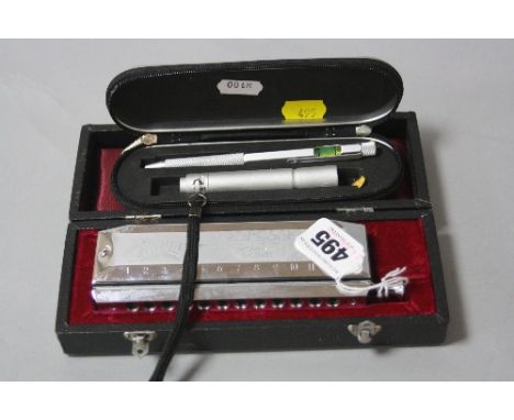 A CASED 'HUANG' HARMONICA and cased pen and torch set