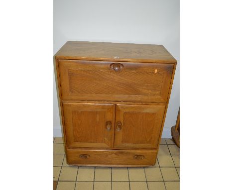 AN ERCOL ELM FALL FRONT BUREAU, above a long drawer and cupboard