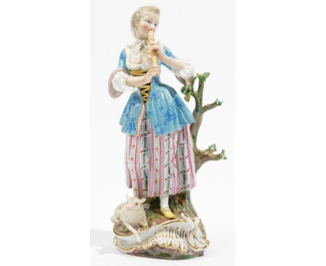 A Meissen figure of a shepherdess, late 19th century, standing against a tree stump playing the recorder, a lamb recumbent at