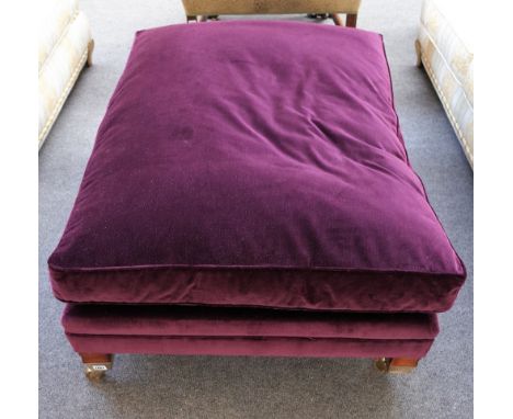 Duresta; a rectangular footstool with loose cushion top, on block supports and heavy lacquered brass castors, 120cm wide x 35