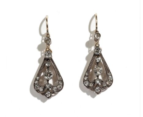 A pair of gold backed and silver set diamond pendant earrings, each in a scroll pierced tapered design, mounted with cushion 