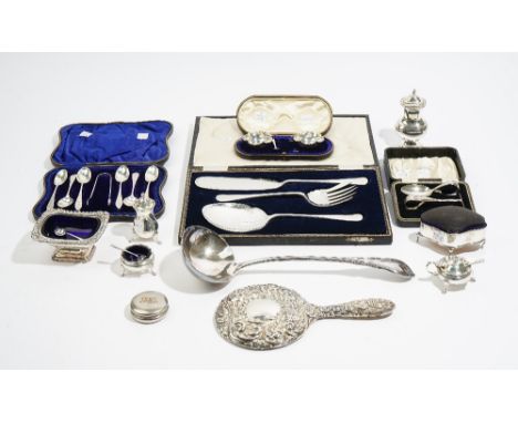 Silver and silver mounted wares, comprising; a hand mirror with embossed decoration, a pin cushion frame box, raised on four 