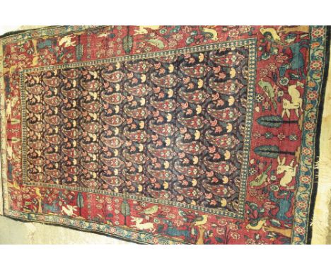 A Tehran rug, Persian, the dark indigo field with rows of botehs; a burgundy border of trees, birds, hares and hunting dogs, 