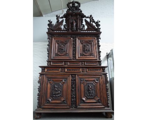 A large early 18th century Italian walnut double height cabinet, with extensive relief carved decoration, the architectural c