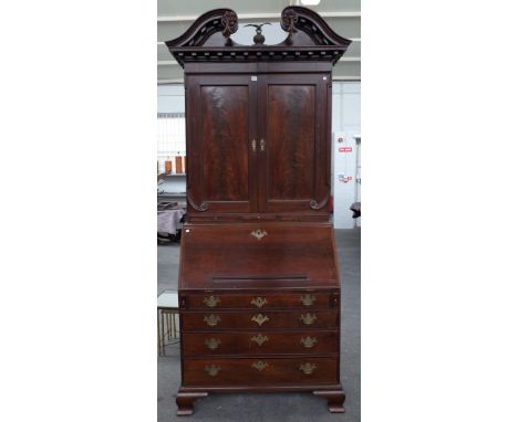 A George III mahogany bureau bookcase, the swan neck cornice over a pair of panelled doors and candle slides, the fitted inte