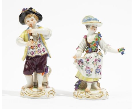 A pair of Meissen figures of vintners, 20th century, a boy playing a recorder, his companion holding grapes, each with a jug 