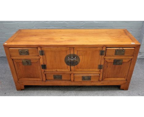 A 19th century Chinese elm low cabinet, with a pair of cupboards and six drawers, on bracket feet, 137cm wide x 63cm wide.