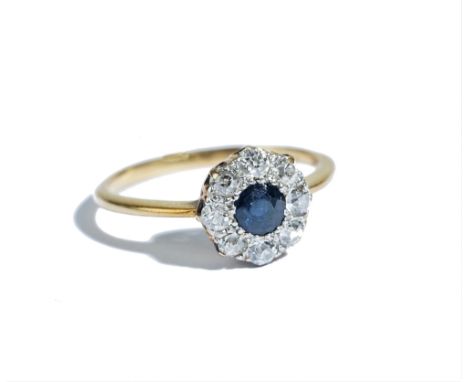 A gold, sapphire and diamond set nine stone cluster ring, mounted with the cushion shaped sapphire at the centre, in a surrou