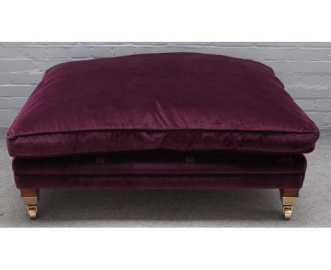 Duresta; a rectangular footstool with loose cushion top, on block supports and heavy lacquered brass castors, 120cm wide x 35
