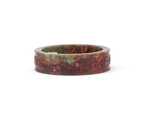 A CHINESE CELADON AND RUSSET JADE BANGLE MING DYNASTY In archaistic style, with black inclusions, the exterior carved in reli