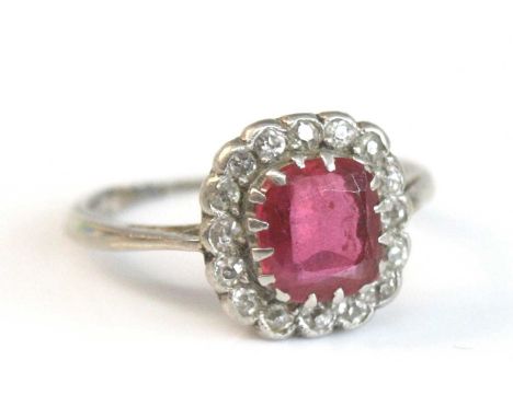 A white metal, ruby and diamond cushion shaped cluster ring, featuring a centre cushion cut ruby within a border of 16 Old Eu