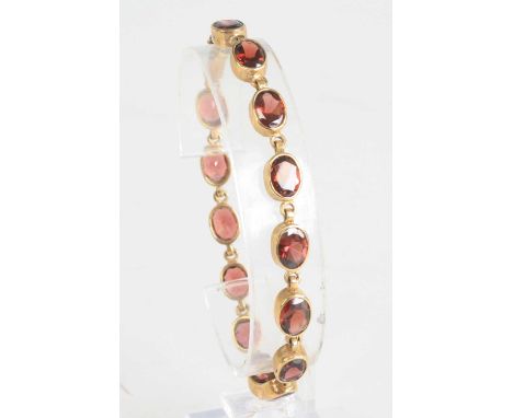 A 9ct gold and garnet set bracelet, arranged as fourteen oval cut and bezel set garnets each measuring approx 8.5 x 5.5mm, 13