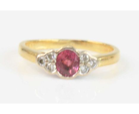 An 18ct yellow and white gold, ruby and diamond ring, featuring a centre oval faceted ruby with a trefoil of round brilliant 