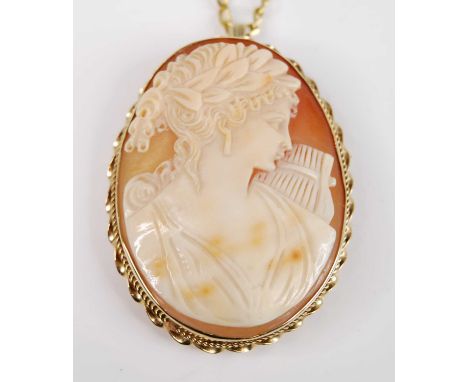 A 9ct yellow gold oval shell cameo brooch/pendant, depicting a classical female with a harp within a ropetwist surround, with