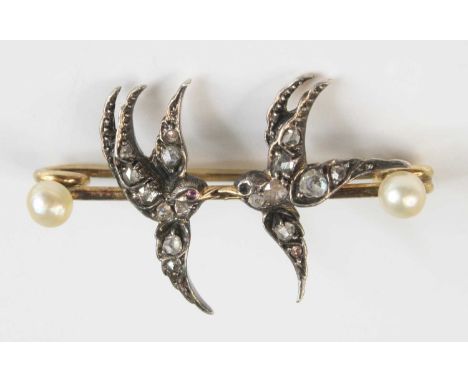 An Edwardian yellow metal, diamond and cultured pearl set safety pin brooch, adorned with two swallows each set with graduate