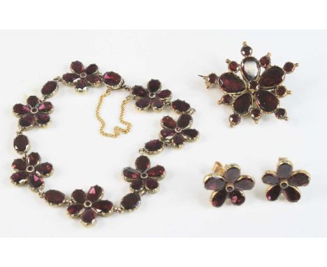 A yellow metal garnet suite, featuring a bracelet of seven flower motifs each with five 6.3 x 4.55mm pear shaped and one 1.95
